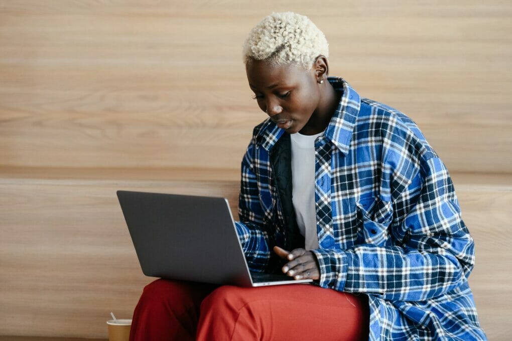 young black woman with stylish haircut working with laptop